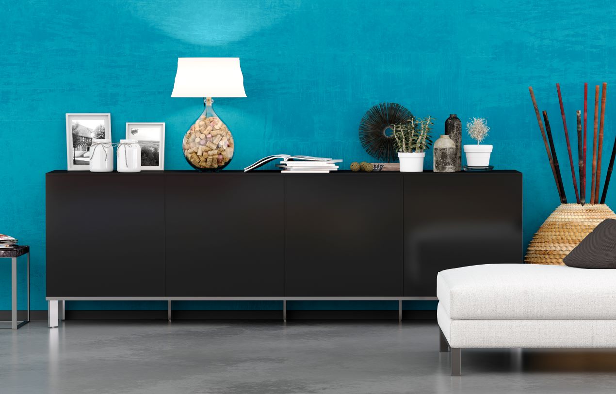 Elegantes, schwarzes Sideboard vor einer leuchtend türkisfarbenen Wand, dekoriert mit Pflanzen, Bildern und einer Designer-Lampe – perfekter Kontrast für moderne Wohnräume.