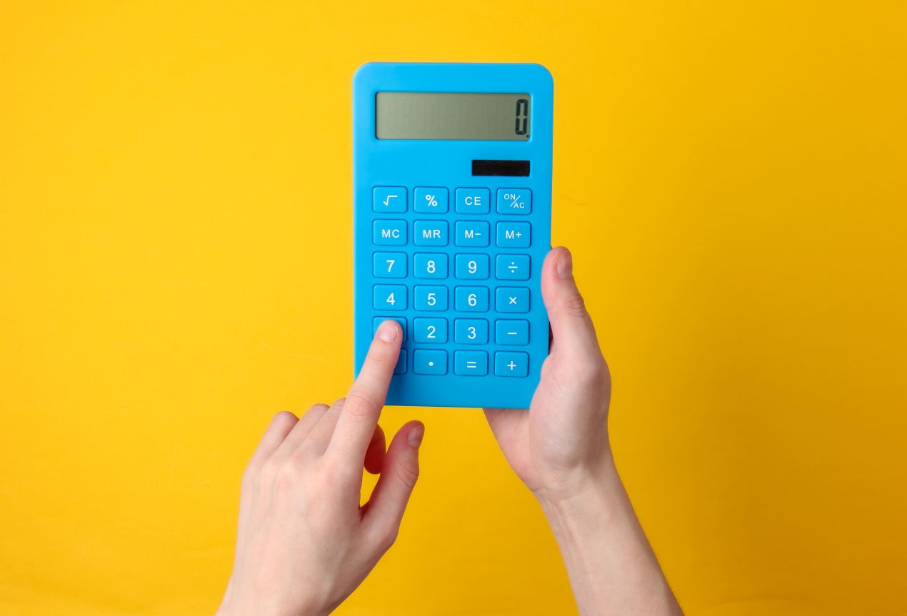 Blaue Taschenrechner in Händen vor gelbem Hintergrund – effektive Nachhilfe online Mathe mit digitalen Tools.