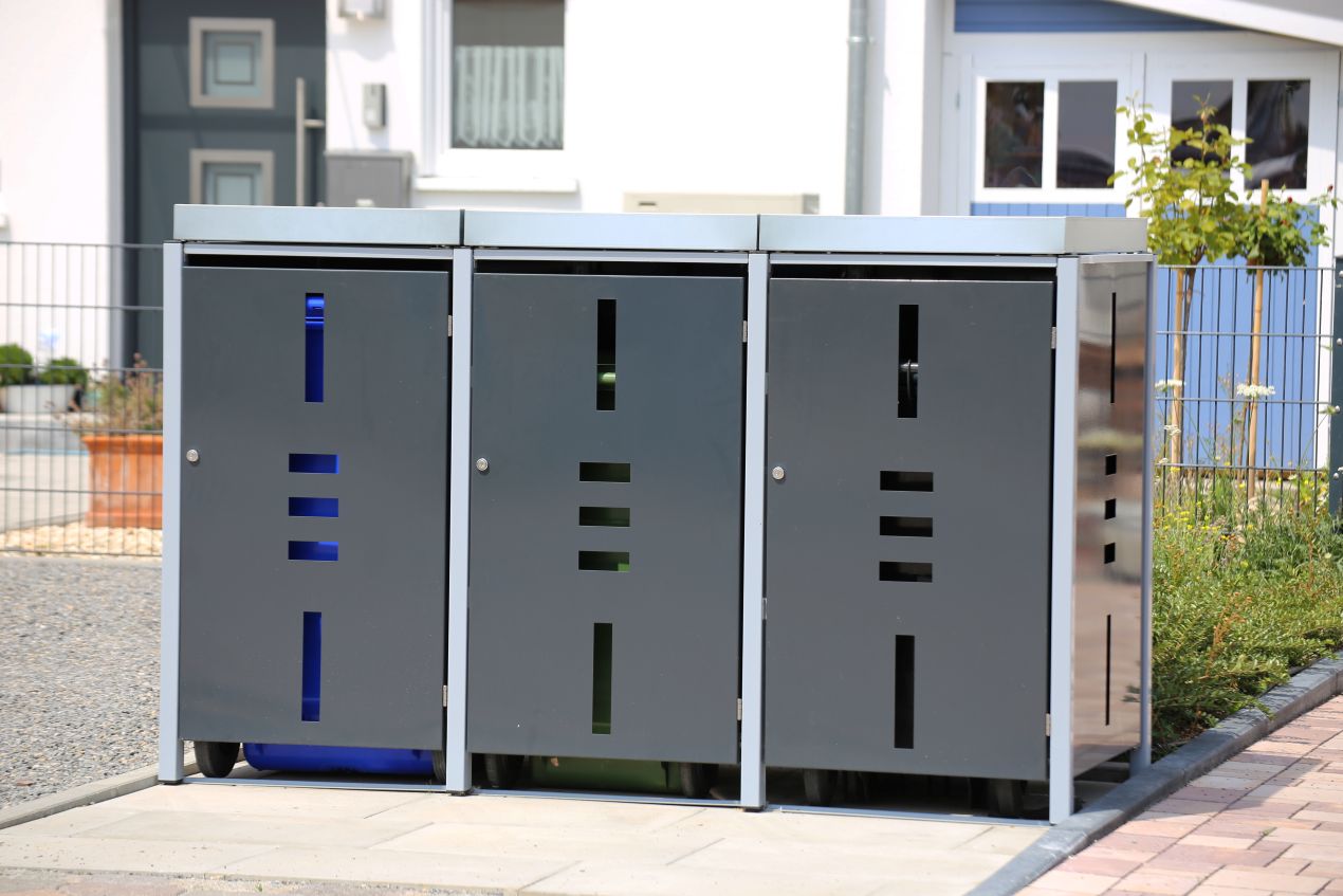 Mülltonnenbox mit anthrazitfarbener Front und gelasertem Muster auf Neubau-Grundstück