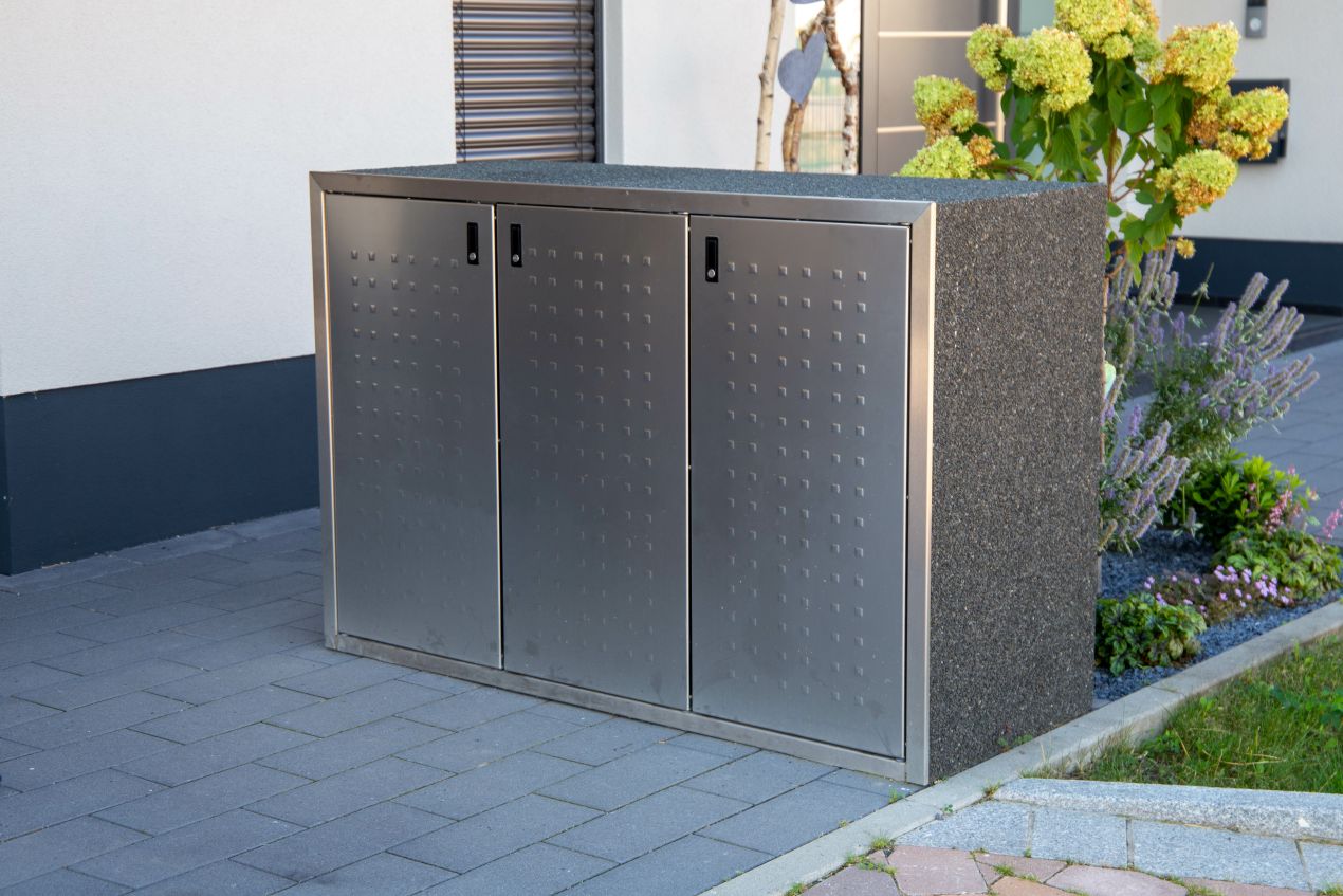Stilvolle Mülltonnenbox aus Edelstahl mit robuster Steinverkleidung im Vorgarten
