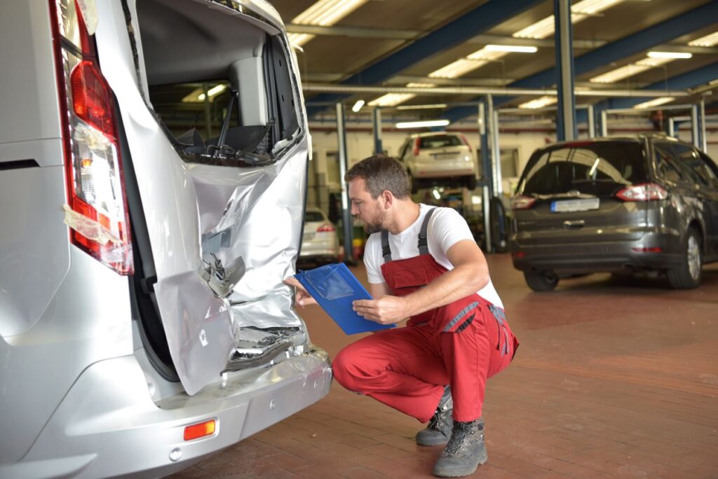mechaniker inspiziert verbeulte heckklappe und dokumentiert schaeden fuer einen kfz sachverstaendiger viernheim